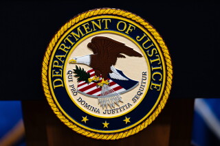 The U.S. Department of Justice logo is seen on a podium before a news conference, May 4, 2026, in Washington. (AP Photo/Julia Demaree Nikhinson, File)