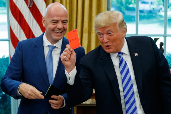 President Donald Trump holds up a red card during a meeting with FIFA president Gianni Infantino in the Oval Office of the White House, Tuesday, Aug. 28, 2018, in Washington. (AP Photo/Evan Vucci, File)
