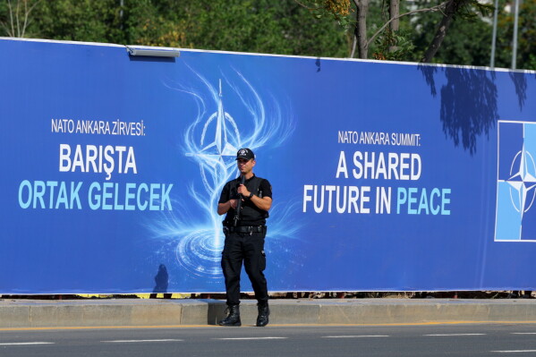 Police patrol in front of a banner ahead of the NATO Summit in Ankara, Turkey, Sunday, July 5, 2026. (AP Photo/Riza Ozel)