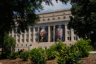 Banners of former President George Washington and President Donald Trump hang above an entrance to the Department of the Interior, Thursday, June 25, 2026, in Washington. (AP Photo/Carolyn Kaster)